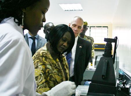 A KWS member of staff at the laboratory explains to Cabinet Secretary Prof. Judi Wakhungu and other dignitaries the process of operation of a gel electrophoresis machine and UV visualizer to view DNA results